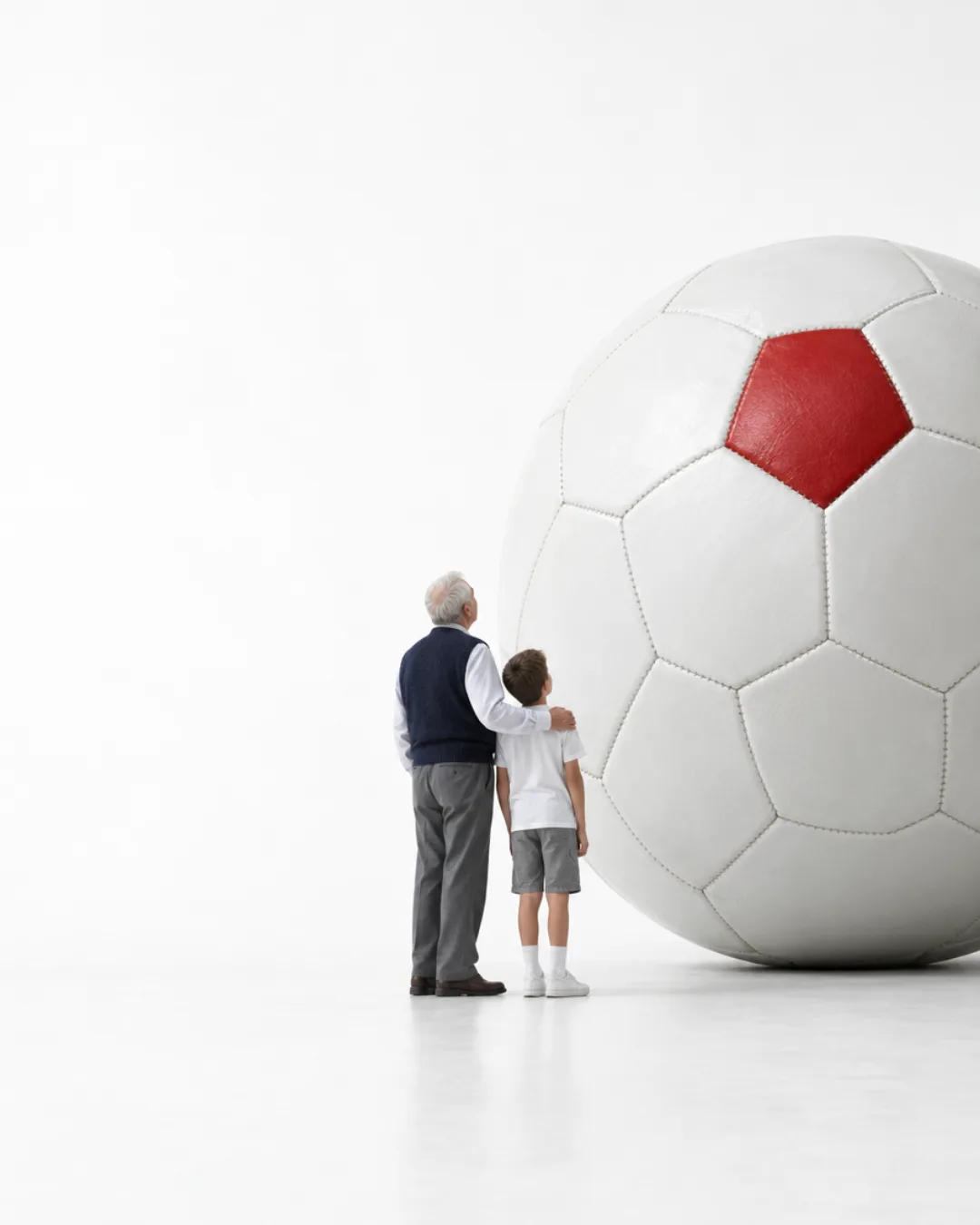 Dev bir futbol topunun önünde duran bir dede ve torunu